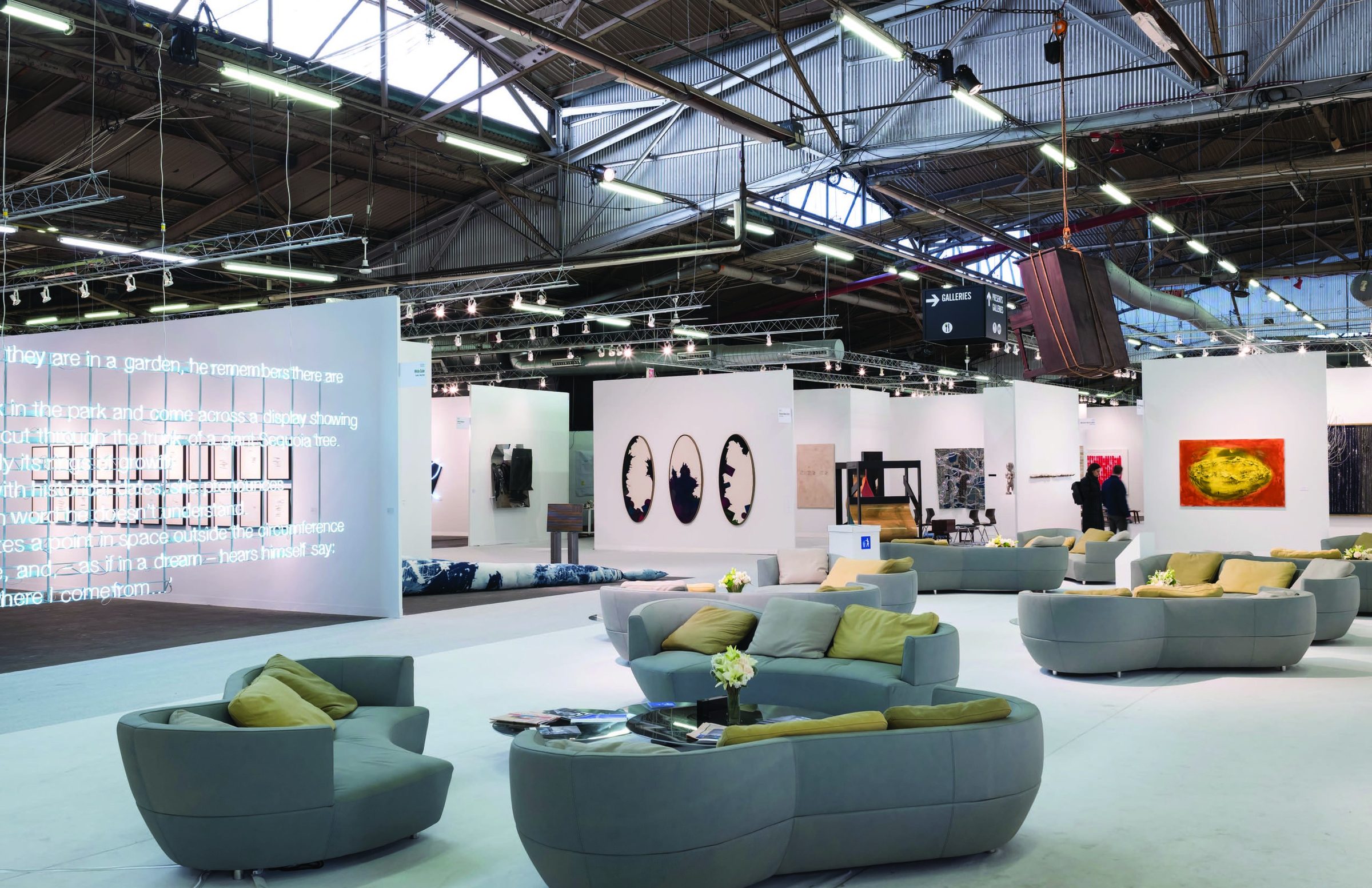 The Armory Show — VIP lounge with curved sofas and a neon text-work wall