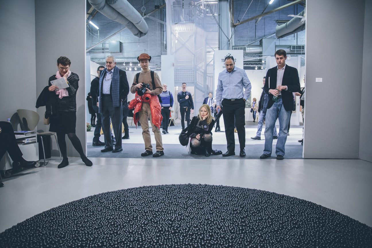 The Armory Show — floor installation of black spheres with visitors looking on